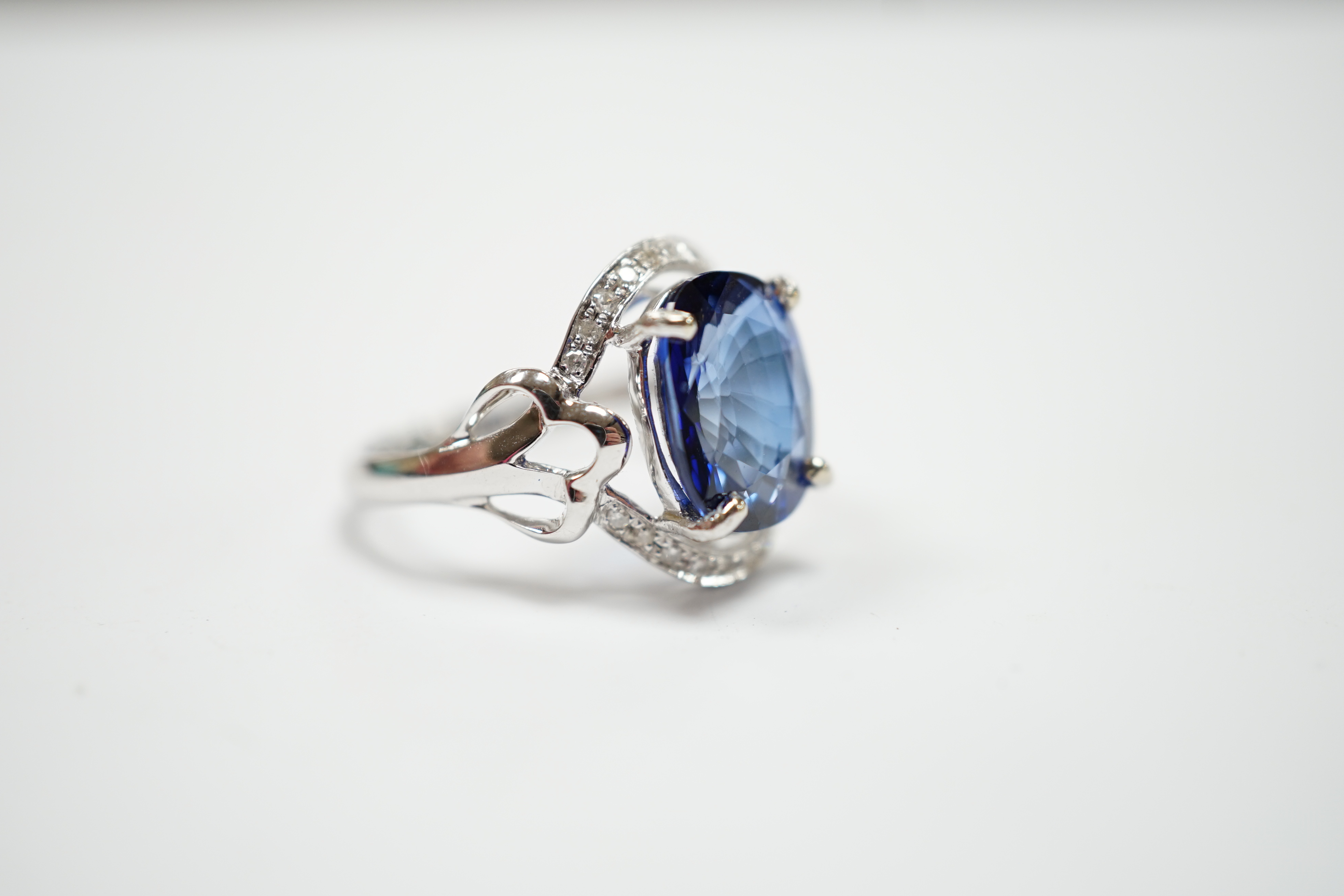 A modern 10k white metal, sapphire and diamond chip set oval cluster set dress ring, size M, gross weight 3.7 grams.